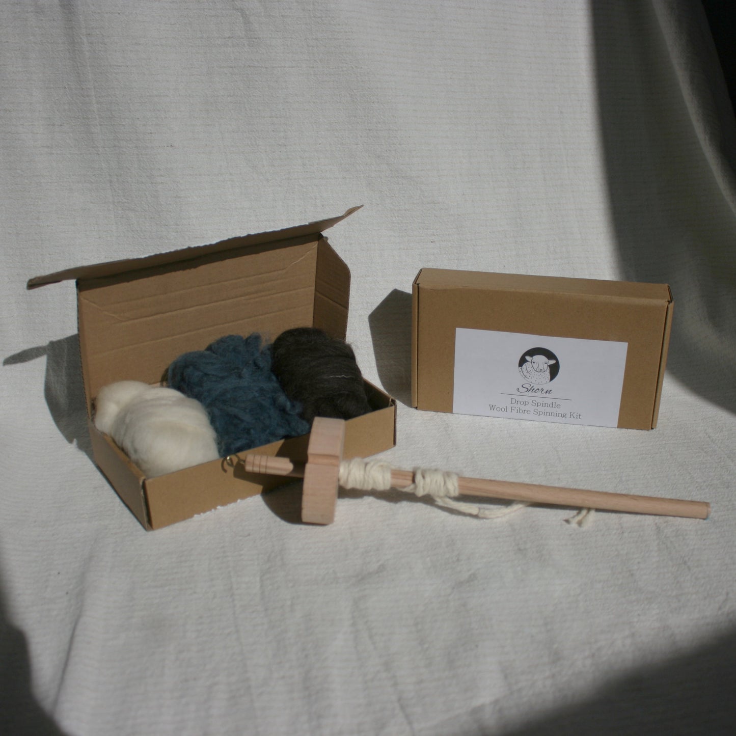 Cardboard box with yarn spinning tools and carded wool balls