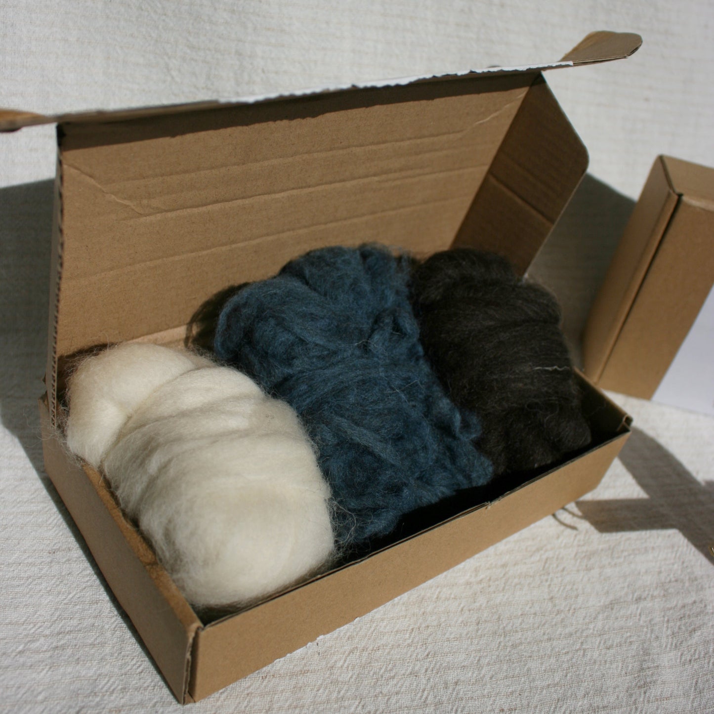 Three balls of wool fibres in a cardboard box