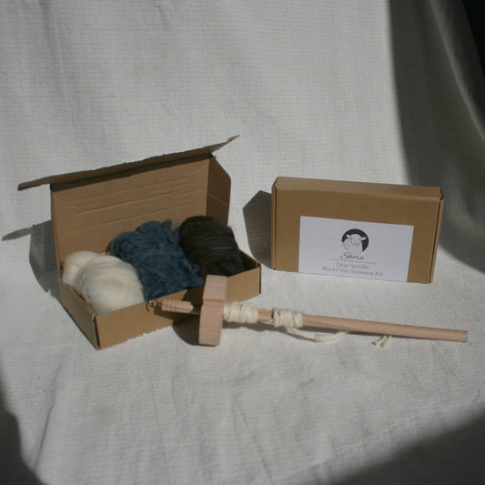 Cardboard box with yarn spinning tools and carded wool balls 